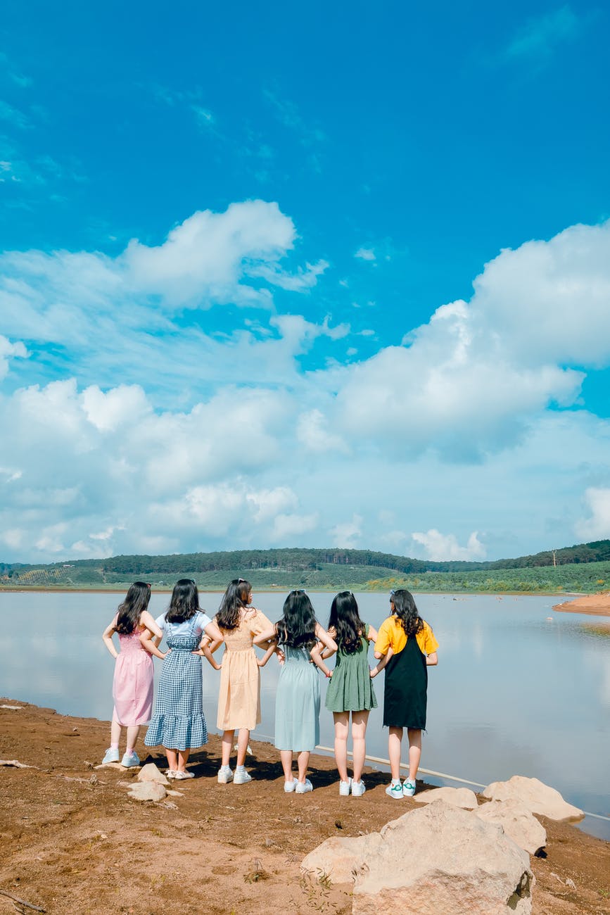 six women facing body of water taking picture