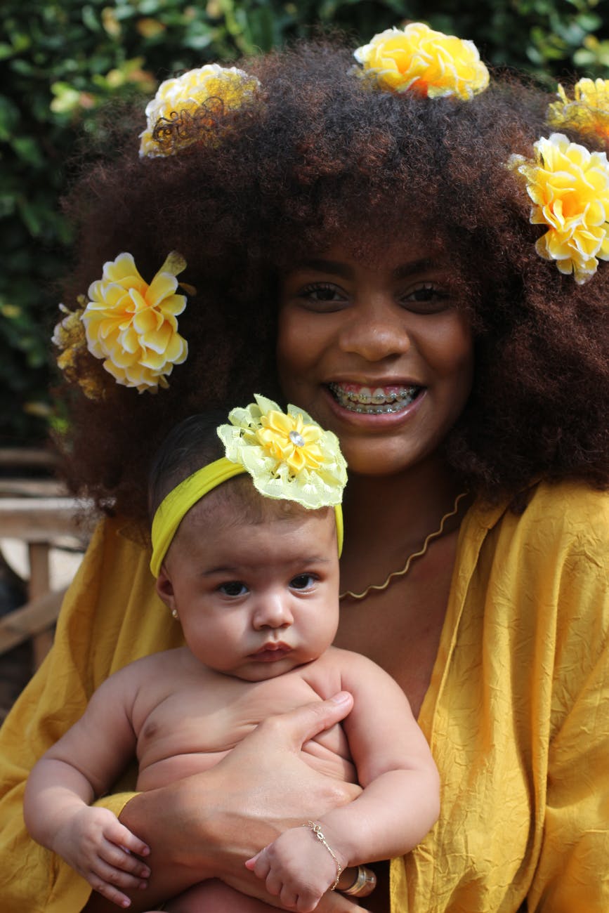 woman with a yellow dress holding a baby