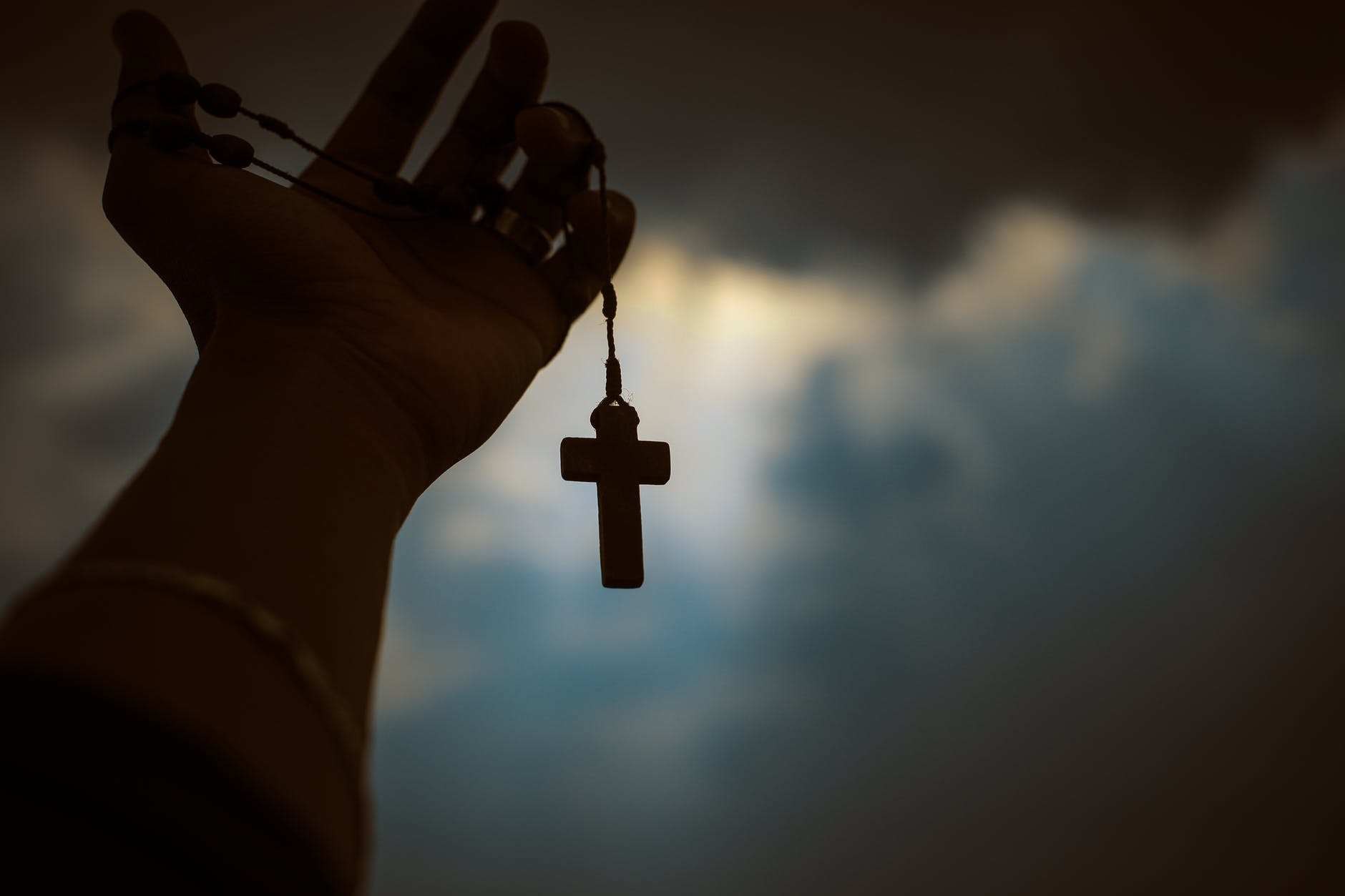 person holding brown wooden cross