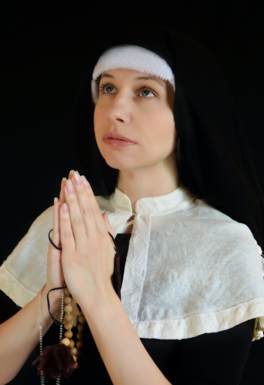 calm nun praying in traditional outfit