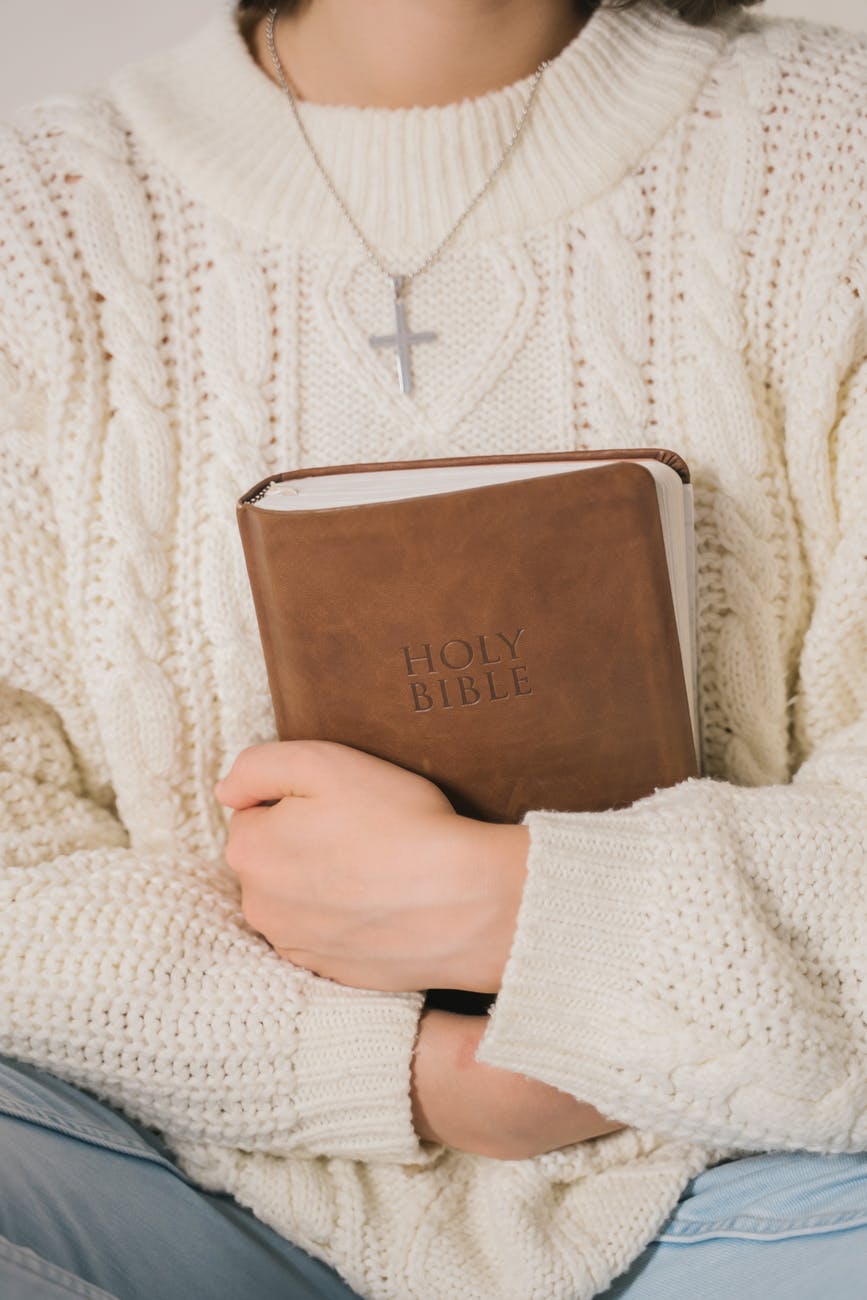 woman in white sweater holding brown leather book