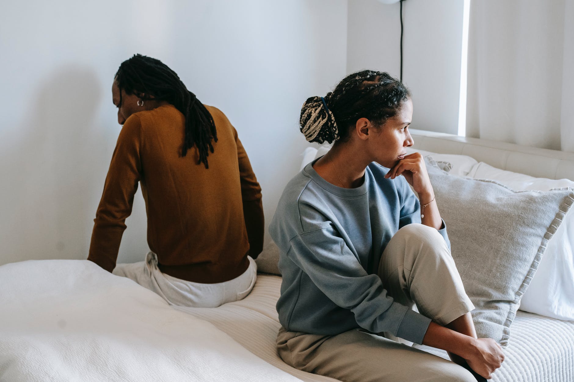 displeased black woman with unrecognizable boyfriend during conflict on bed