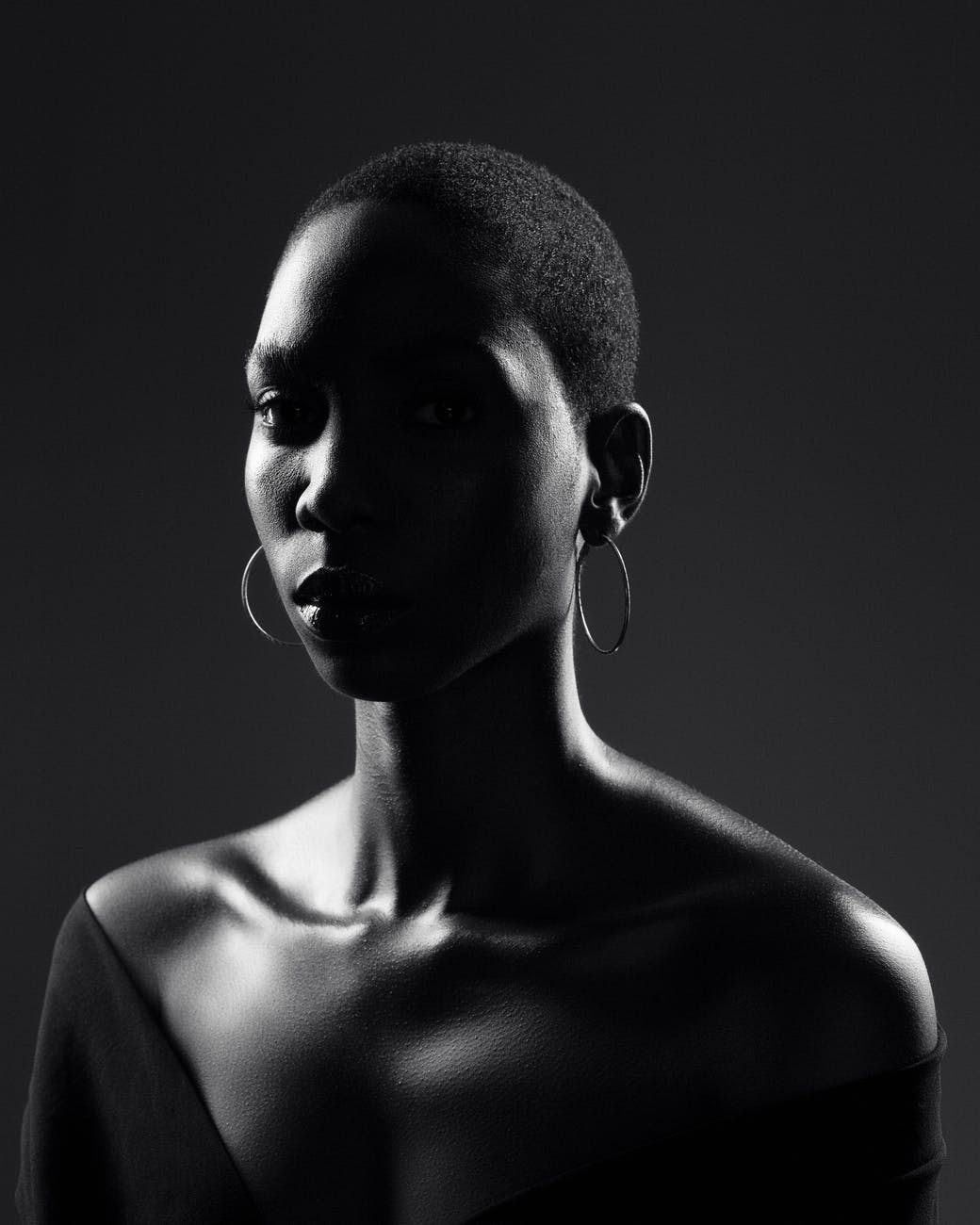 calm black woman with bare shoulders against dark background