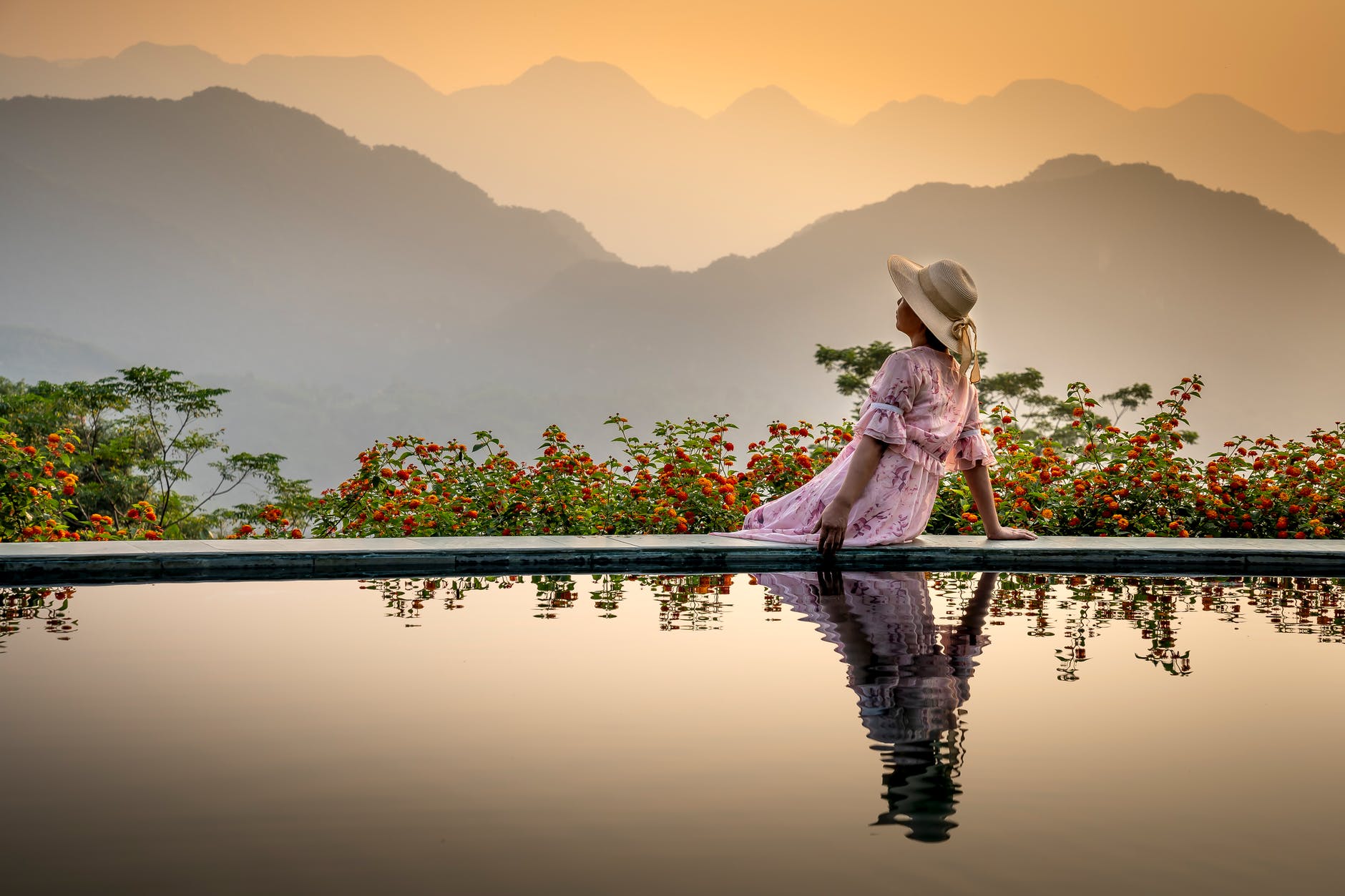 unrecognizable lady admiring sunset on poolside