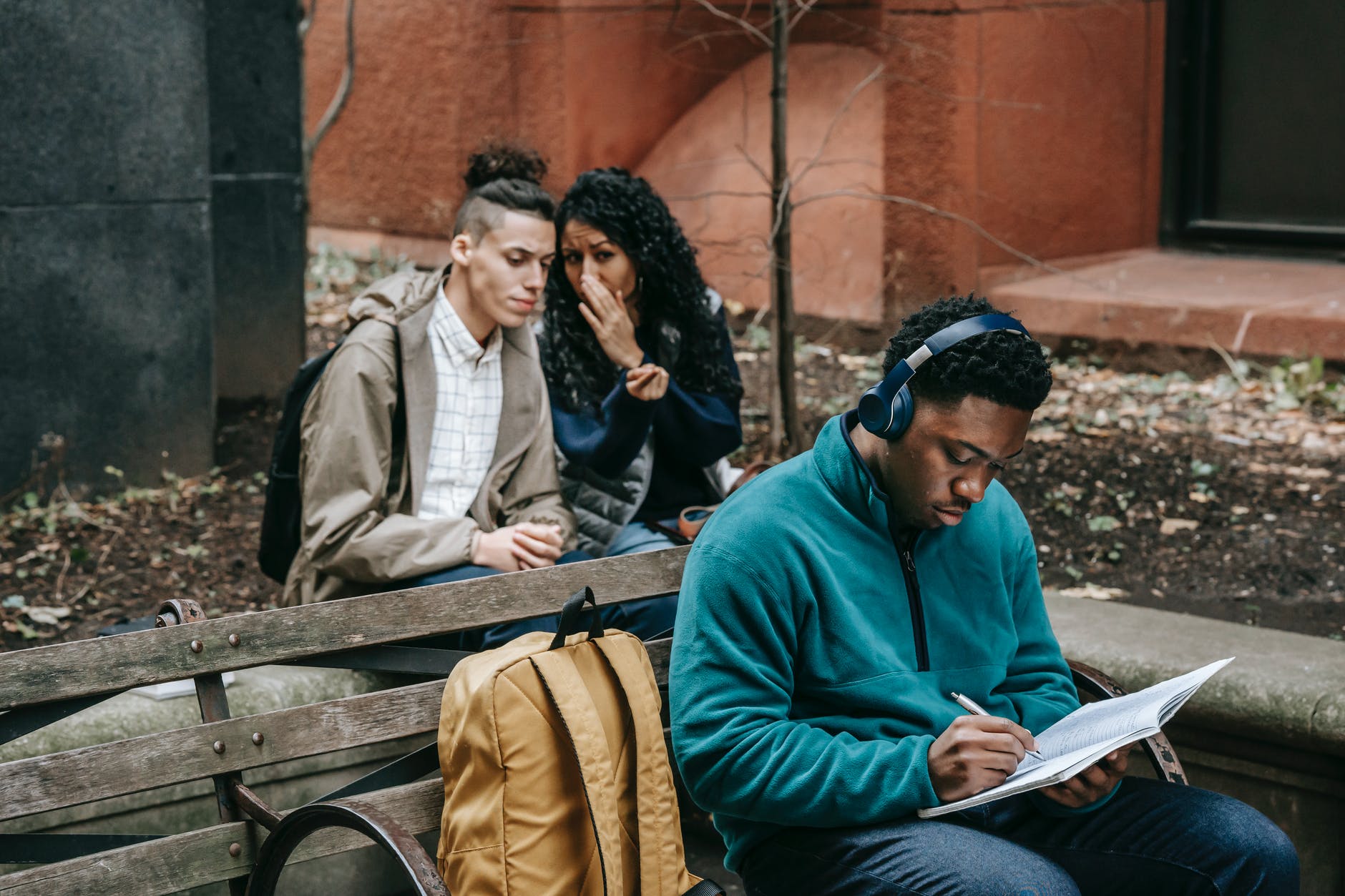 multiethnic friends gossiping behind attentive classmate