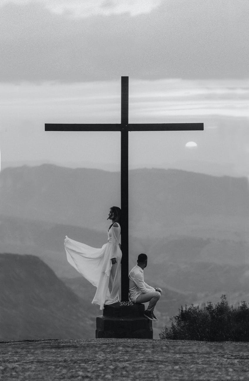 man and woman pose on a cross monument