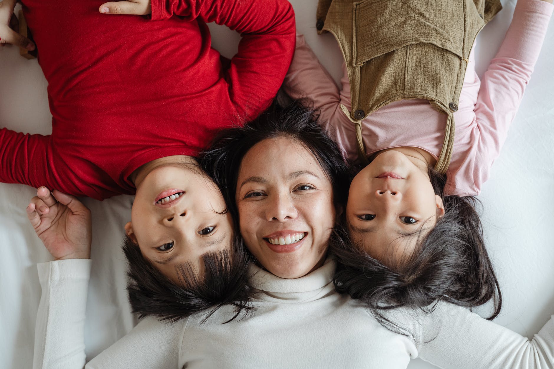 photo of woman and her children lying on bed