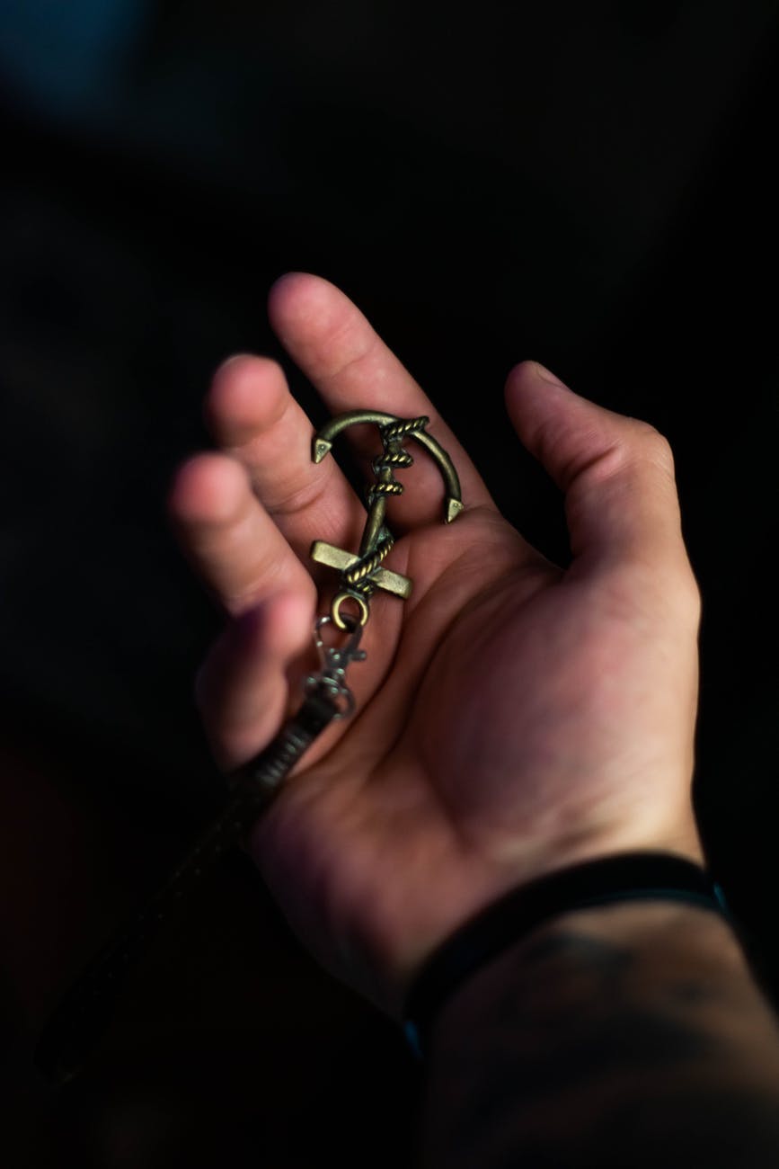 crop unrecognizable man demonstrating anchor keychain on palm