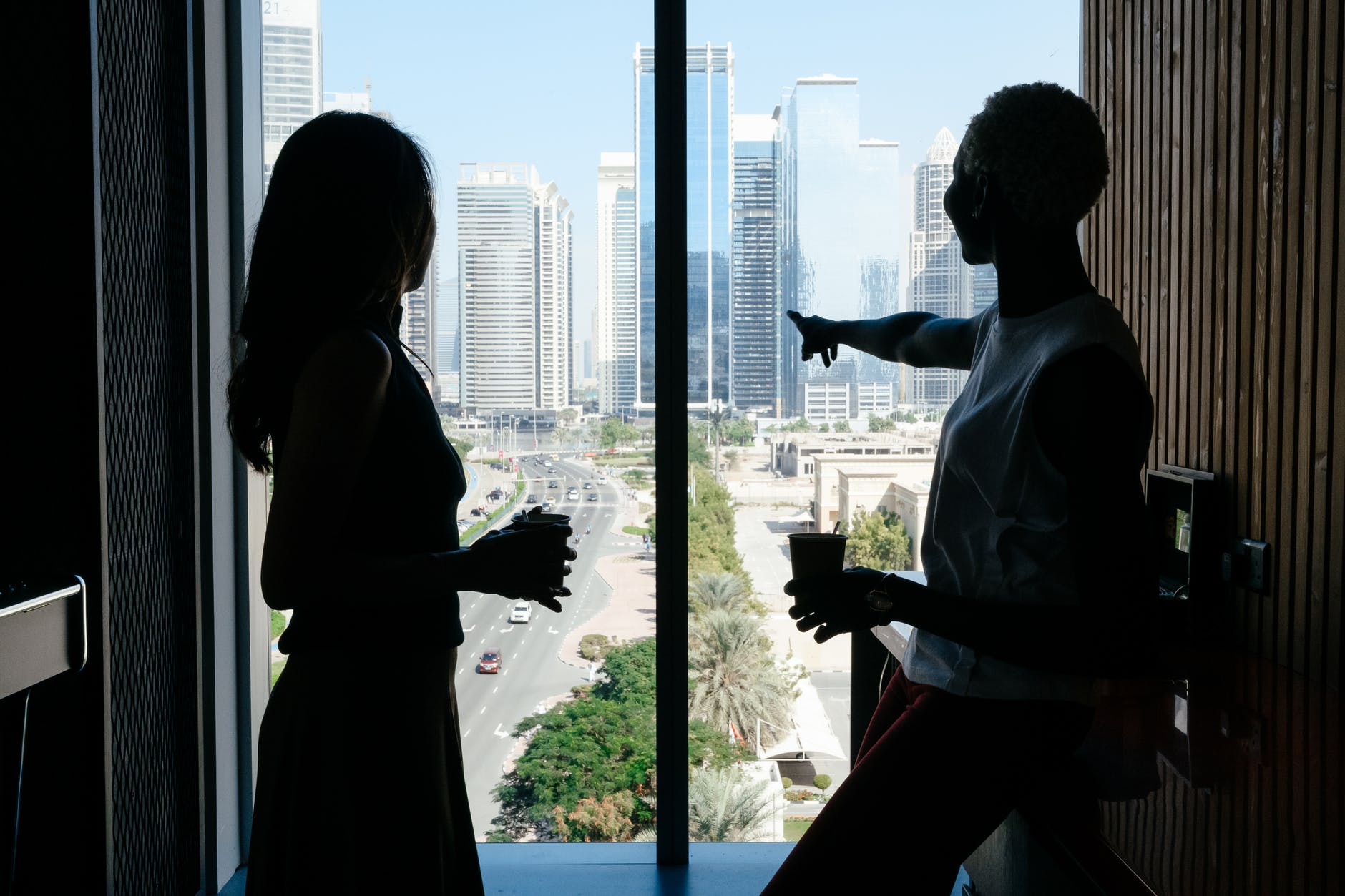 black woman pointing away at skyscrapers and talking with colleague