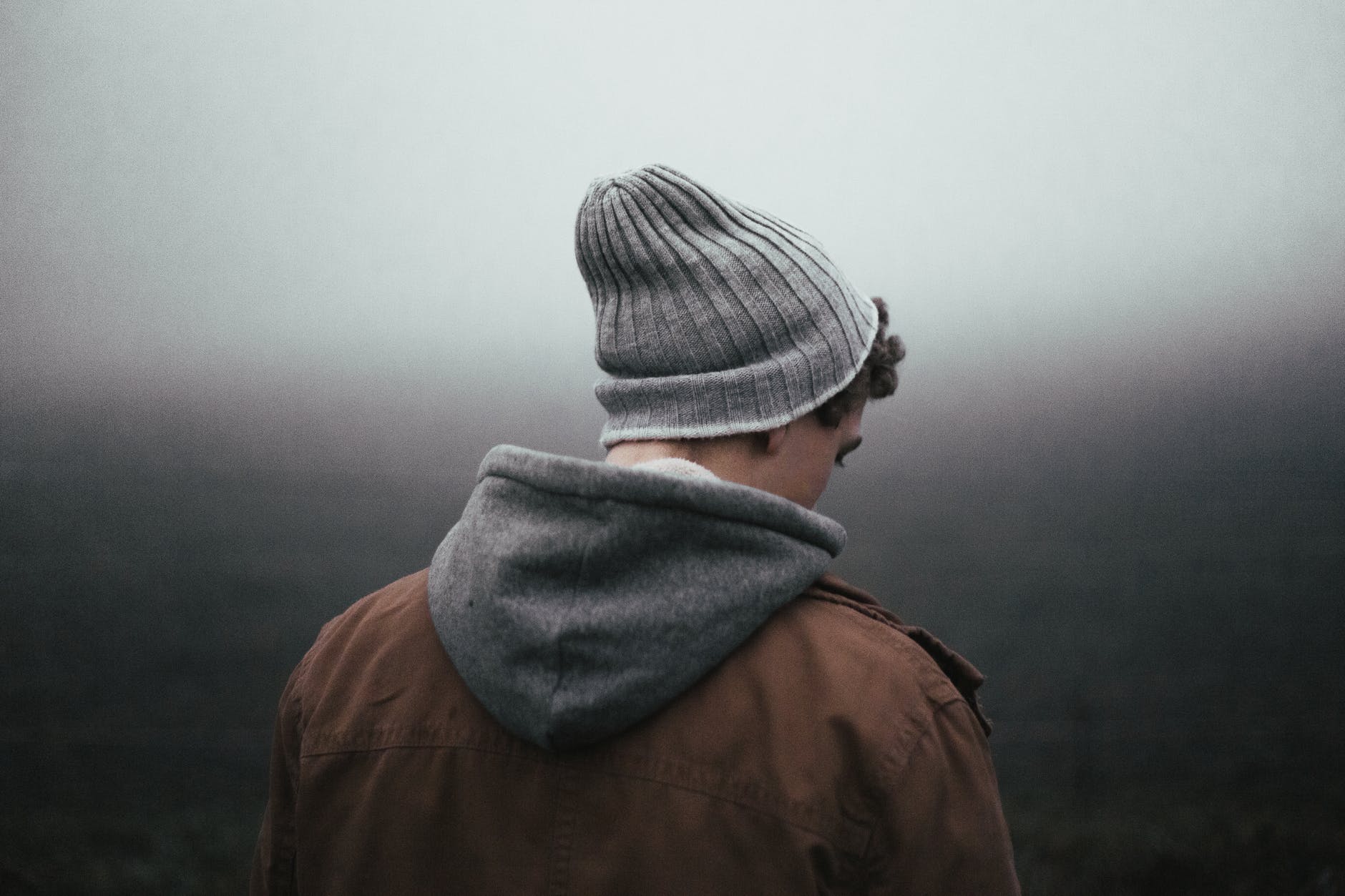 person in gray knit cap and brown jacket