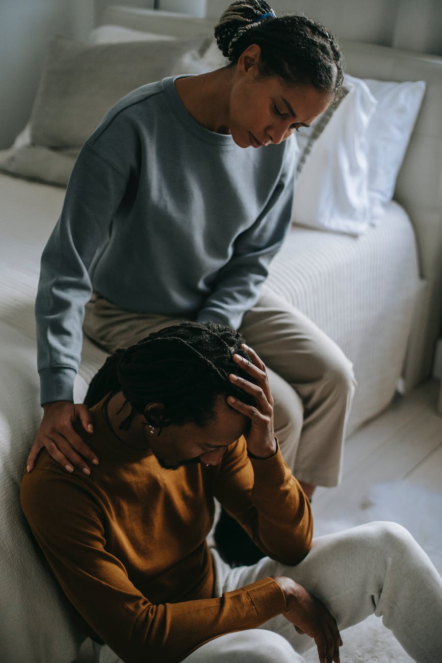 black wife supporting depressed unhappy husband in bedroom